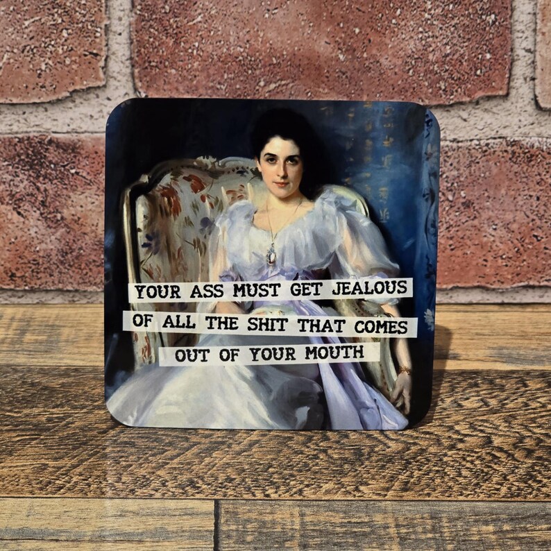 May include: Square coaster featuring a vintage portrait of a woman in a flowing lavender dress. The text on the coaster reads: "YOUR ASS MUST GET JEALOUS OF ALL THE SHIT THAT COMES OUT OF YOUR MOUTH."