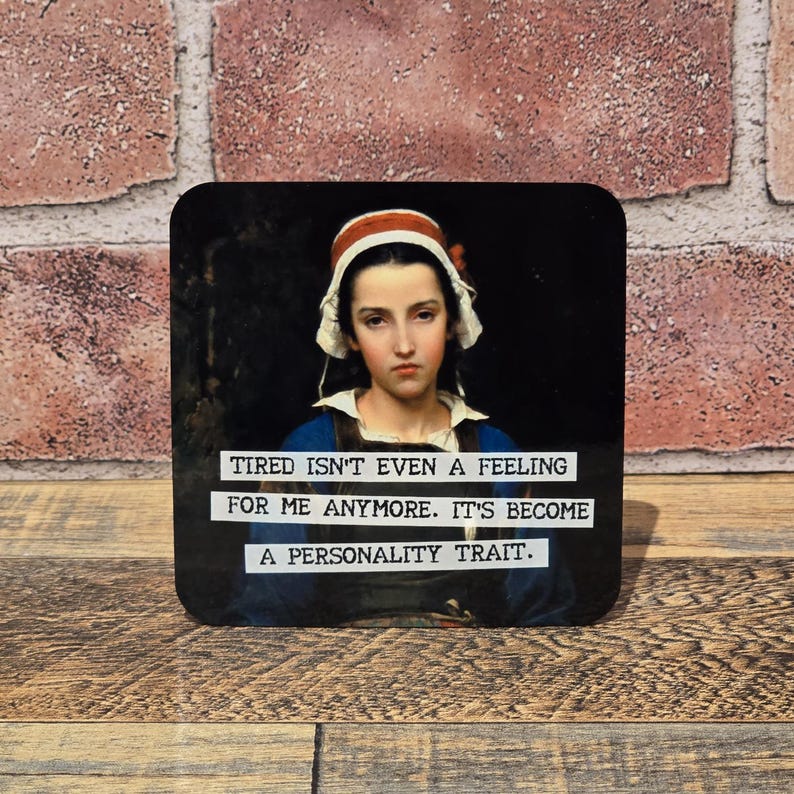 May include: Square coaster featuring a portrait of a woman in a white bonnet and blue dress. The coaster has the text: "TIRED ISN'T EVEN A FEELING FOR ME ANYMORE. IT'S BECOME A PERSONALITY TRAIT."