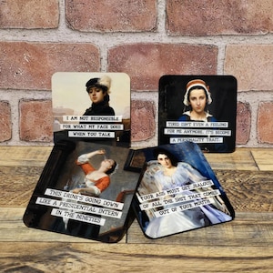 May include: Four square coasters with vintage art prints and humorous text. One coaster reads "I AM NOT RESPONSIBLE FOR WHAT MY FACE DOES WHEN YOU TALK." Another says "TIRED ISN'T EVEN A FEELING FOR ME ANYMORE. IT'S BECOME A PERSONALITY TRAIT."