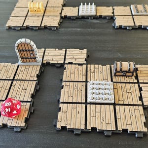 Peut inclure: Mise en place pour un jeu de r&ocirc;le sur table avec des dalles de sol en bois, des figurines miniatures et des accessoires de jeu. Comprend un d&eacute; rouge &agrave; vingt faces, une porte miniature, des coffres au tr&eacute;sor et un panneau.