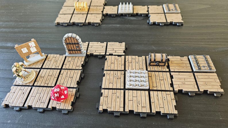 Peut inclure: Mise en place pour un jeu de r&ocirc;le sur table avec des dalles de sol en bois, des figurines miniatures et des accessoires de jeu. Comprend un d&eacute; rouge &agrave; vingt faces, une porte miniature, des coffres au tr&eacute;sor et un panneau.