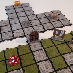 Peut inclure: Terrain de jeu de table modulaire avec des dalles de pierre grise et d'herbe verte. Comprend des coffres au tr&eacute;sor miniatures, une porte en bois, un panneau, une figurine et un d&eacute; rouge &agrave; vingt faces. Id&eacute;al pour les jeux de r&ocirc;le.