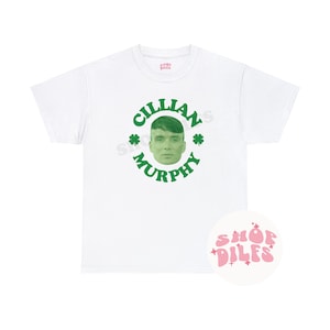 May include: White t-shirt featuring a green graphic of Cillian Murphy's face surrounded by the text "Cillian Murphy" and shamrocks. A pink and white Shop DILFS logo is on the bottom right.