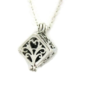 May include: A silver chain necklace with a small, square, openwork pendant. The pendant has a delicate, floral design.