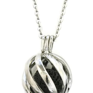 May include: Silver chain necklace with a silver cage pendant containing a black lava rock. The cage is designed with a swirl pattern.