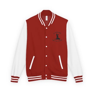May include: A red and white varsity jacket with a button-up front. The jacket has white sleeves, a white collar, and white stripes on the cuffs and hem. A black graphic and text are on the left chest.