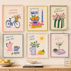 May include: A set of six framed wall art prints featuring colorful illustrations of a bicycle, fruit, flowers, a coffee pot, a martini glass, and text including Amore Sempre, Merci Beaucoup, Matin Calme, Ciao Sole, and Petit Bonheur in scalloped frames.