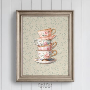 May include: A framed art print showing a stack of five decorative teacups and a saucer. The teacups have floral and gingham patterns in pink, white, and gold. The background is a light beige with a subtle leaf pattern. The frame is light brown.