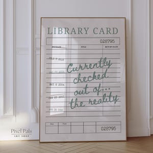 May include: A framed print designed as a library card, with the words "Currently checked out of... the reality" in a handwritten font. The print is set in a brown frame against a white wall, with the text in a light green colour.