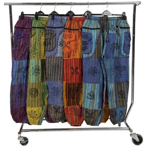 Może przedstawiać: Różne kolorowe spodnie patchworkowe wiszące na metalowym wieszaku. Każda para ma unikalną kombinację kolorów i wzorów, w tym paski, kwiatowe wzory i kieszenie. Spodnie są wykonane z lekkiego materiału.