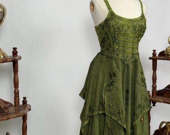 May include: A green dress with a layered skirt and a corset-style bodice is displayed on a mannequin. The dress has a floral pattern and spaghetti straps. The fabric appears to be a soft, textured material.