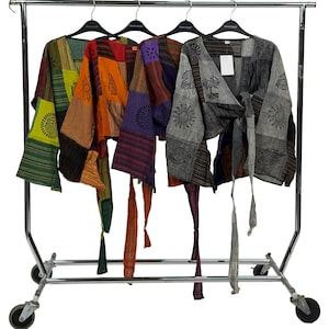 Könnte beinhalten: Vier bunte Patchwork-Kimono-Jacken hängen an einem rollenden Kleiderständer. Jede Jacke hat eine einzigartige Kombination aus Mustern und Farben, darunter Grün, Orange, Lila und Grau. Die Jacken haben Bindebänder und sind mit Sonnen- und Baumdesigns verziert.