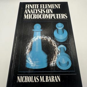 May include: A hardcover book titled "Finite Element Analysis on Microcomputers" by Nicholas M. Baran. The cover is black with white text and features blue geometric shapes. The book appears to be a technical or academic text.