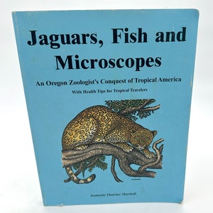 Peut inclure: Une couverture de livre bleue avec le titre "Jaguars, poissons et microscopes : La conquête de l'Amérique tropicale par un zoologiste de l'Oregon avec des conseils de santé pour les voyageurs tropicaux" et une illustration d'un jaguar sur une branche d'arbre.