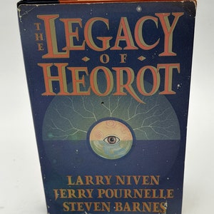 May include: A blue hardcover book with the title "The Legacy of Heorot" in gold lettering. The authors are Larry Niven, Jerry Pournelle, and Steven Barnes.