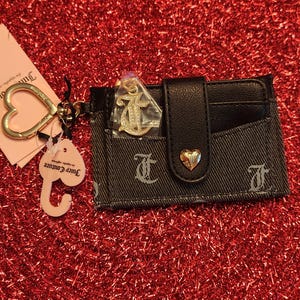 Estuche para tarjetas alargado con pestaña Pack It Up de Licorice de Juicy Couture, elegante cartera vaquera negra con logotipo brillante y llavero con forma de corazón.