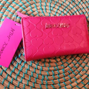 Cartera plegable XOIVY rosa de Betsey Johonson con corazones acolchados por toda la caja y detalle de logotipo de metal rosa