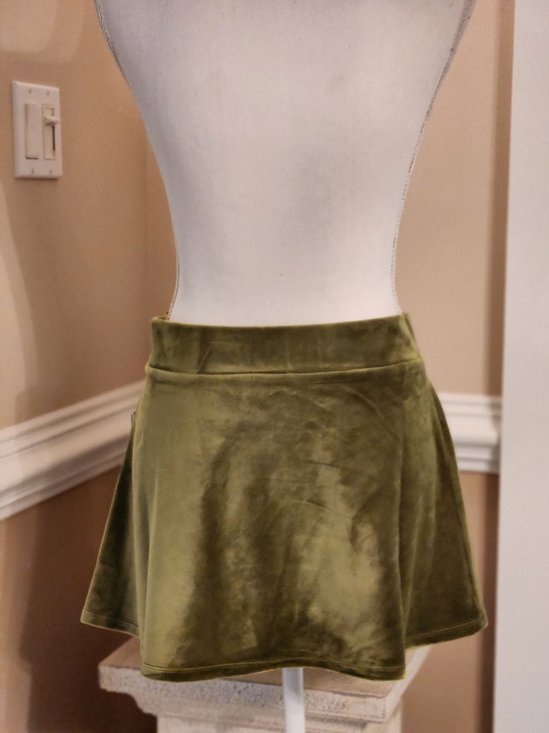 May include: A short, olive green velvet skirt with a flared hem.