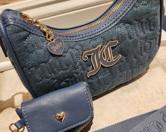 May include: A blue denim shoulder bag and a small matching pouch. The bag has a gold zip, a gold chain with a heart charm, and a gold logo. The pouch has a gold heart charm. The strap has the word "Couture" embroidered on it.