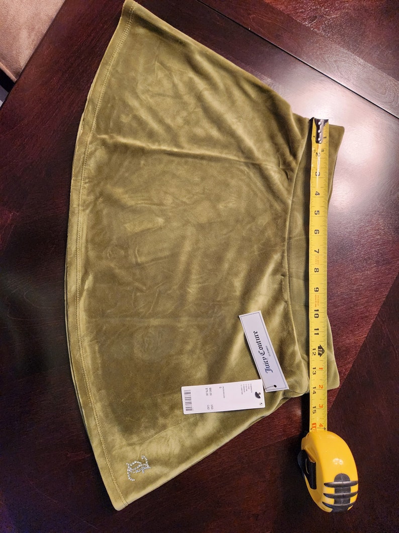 May include: A green velvet skirt with a Juicy Couture tag and a rhinestone logo. The skirt is 15 inches long.