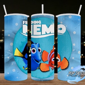 May include: A blue Finding Nemo travel mug with a white straw. The mug features Dory, Nemo, and the movie title. The design includes a blue background with bubbles and the Pop Designs by Adam logo.