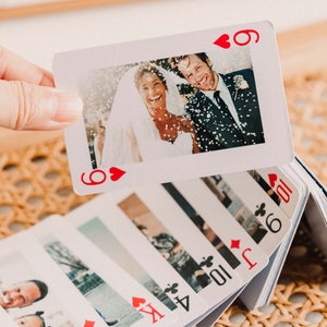 May include: A deck of playing cards with personalized photos on each card. The top card shows a wedding photo of a couple with confetti falling on them. The card is a 6 of hearts.