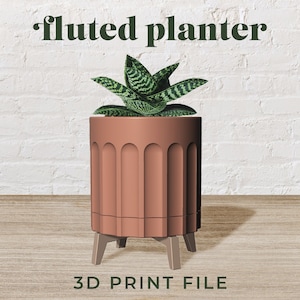 May include: A 3D printable model of a fluted planter with four legs. The planter is a light brown colour and has a plant inside.