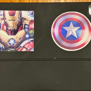 Pu&ograve; includere: Una custodia per iPad nera con un adesivo di Iron Man rosso, oro e blu e un adesivo a forma di scudo di Capitan America rosso, bianco e blu.
