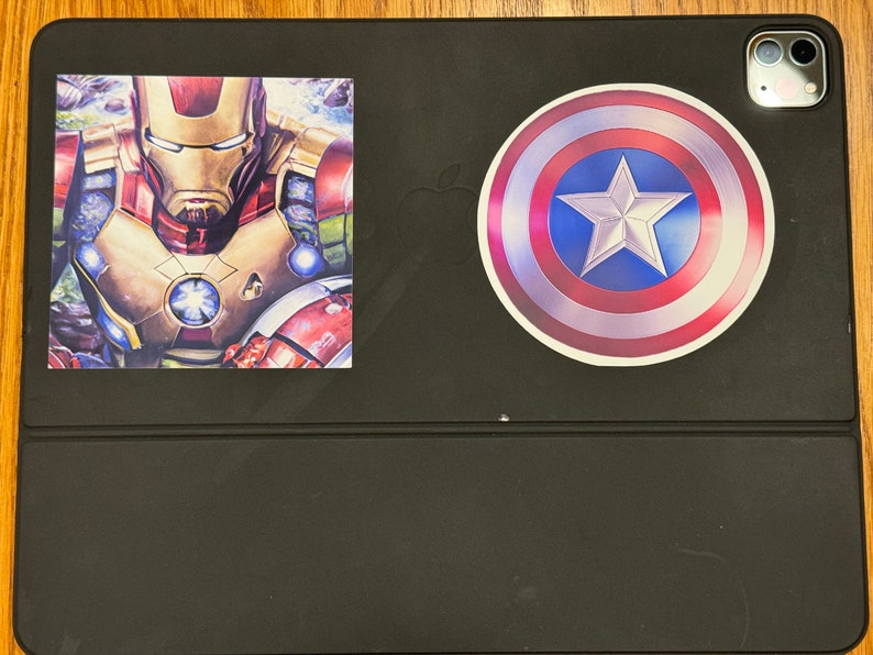 Pu&ograve; includere: Una custodia per iPad nera con un adesivo di Iron Man rosso, oro e blu e un adesivo a forma di scudo di Capitan America rosso, bianco e blu.