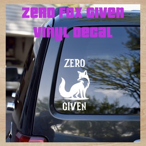 May include: A white vinyl decal with a fox silhouette and the text "ZERO GIVEN". The decal is on the back window of a black car.