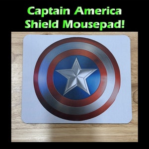 May include: A white mousepad with a red, white, and blue Captain America shield design. The shield has a silver star in the center.