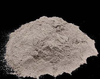 May include: A pile of light gray powder against a black background. The powder has a fine, granular texture and appears to be a bulk ingredient. The image is a close-up shot, highlighting the texture and color of the powder.