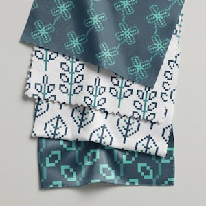 May include: Close-up of four fabric swatches with pixelated floral and geometric patterns. The fabrics feature teal and white designs on navy and white backgrounds. The edges of the swatches are frayed.