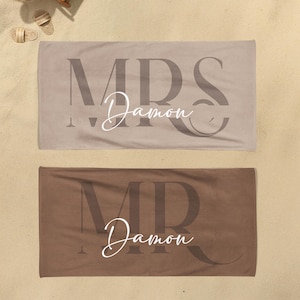 May include: Two rectangular beach towels in beige and brown. The beige towel features the large dark text MRS and the white script text Damon. The brown towel features the large dark text MR and the white script text Damon centered on the fabric.