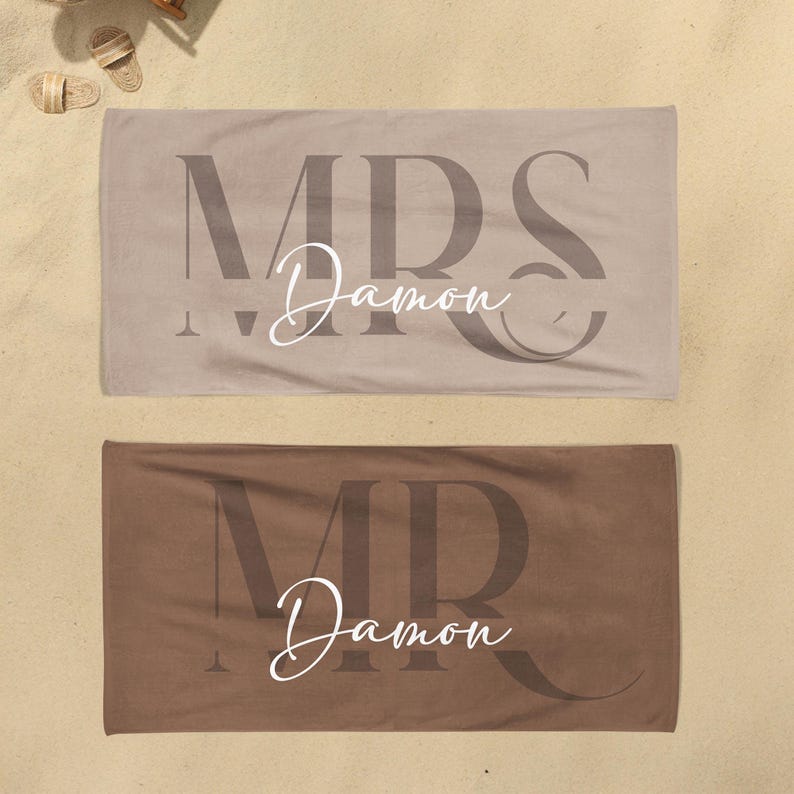 May include: Two rectangular beach towels in beige and brown. The beige towel features the large dark text MRS and the white script text Damon. The brown towel features the large dark text MR and the white script text Damon centered on the fabric.