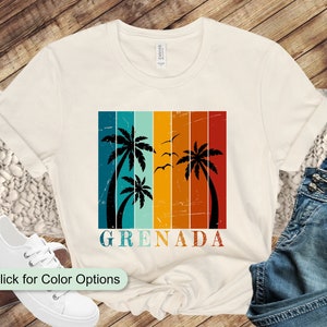 Może przedstawiać: Biały t-shirt z grafiką w stylu vintage przedstawiającą palmy i napis "GRENADA" na kolorowym, pasiastym tle.