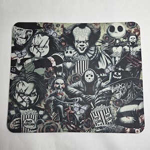 May include: A colorful mousepad featuring a collage of horror movie characters, including Freddy Krueger, Pennywise, Jason Voorhees, and Michael Myers. The characters are holding popcorn and surrounded by roses and butterflies.