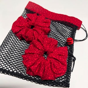 May include: Two red fabric scrunchies with white polka dots in a black mesh drawstring bag with a red toggle closure.