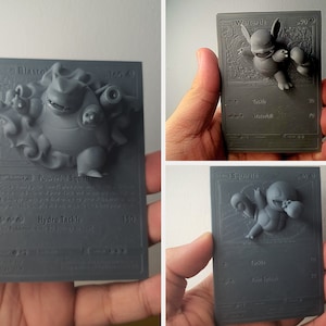 May include: Three 3D printed Pokemon trading cards featuring Blastoise, Wartortle, and Squirtle. The cards are gray and have the Pokemon's name and stats printed on them.