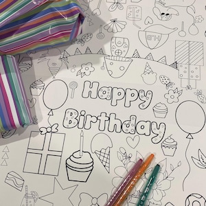以下が含まれることがあります： 「Happy Birthday」の文字と、プレゼント、カップケーキ、風船などのイラストが描かれた白い塗り絵。3色のクレヨンがシートの上にあり、背景にはカラフルなストライプのギフト包装があります。