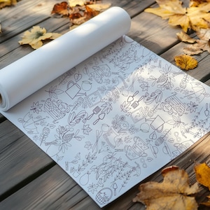 May include: A white roll of wrapping paper with a black and white doodle pattern of gardening tools, plants, and other garden-related items. The paper is unrolled on a wooden surface with autumn leaves scattered around it.