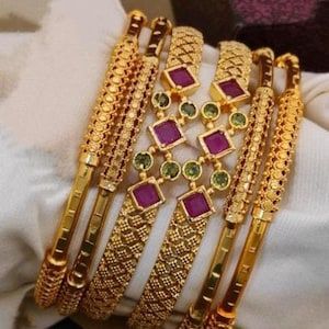 Peut inclure: Un ensemble de six bracelets en or avec des motifs complexes. Les bracelets sont ornés de pierres précieuses roses et vertes.