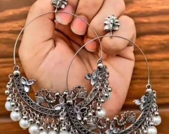 May include: A pair of silver hoop earrings with intricate floral designs and dangling pearl accents.