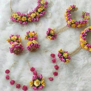 May include: A floral jewellery set with pink and yellow flowers. The set includes a necklace, earrings, a bracelet, and a hairpiece.