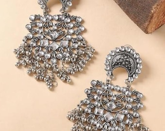 May include: A pair of silver dangle earrings with a crescent moon design and clear rhinestones. The earrings have a beaded fringe.