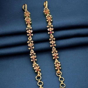 May include: A pair of gold earrings with a dangling design. The earrings are adorned with small, colorful gemstones in a floral pattern.