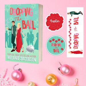 May include: A pink background with a book cover that says "Dropping the Ball" with a disco ball and people in the background. There are also stickers with the same title and a red flower sticker that says "Austin".