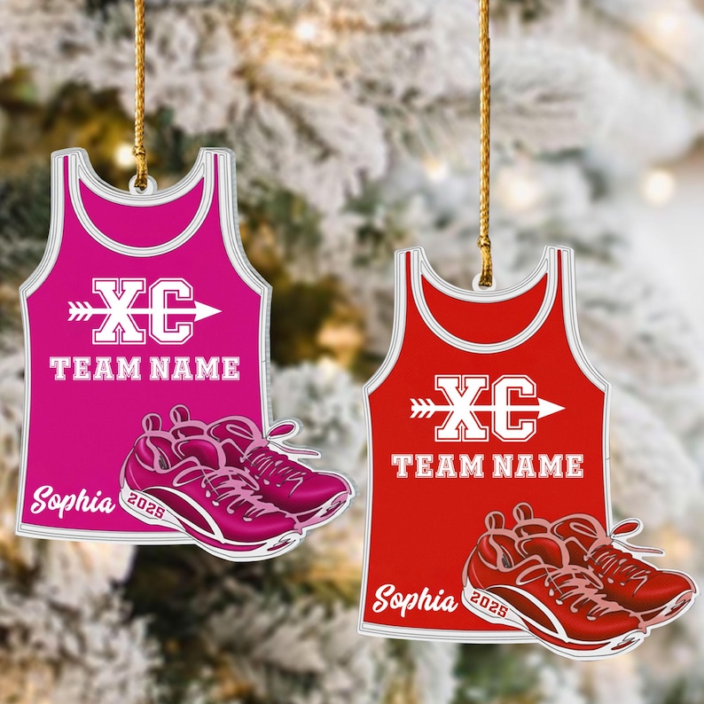 May include: Two cross country running themed ornaments. One is hot pink, the other is red. Each features a tank top design with "XC" and "TEAM NAME" in white, plus a pair of running shoes. The name "Sophia" and the year "2025" are also printed.