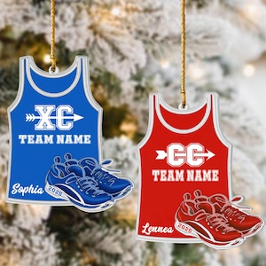 May include: Two athletic ornaments. One is blue with "XC" and "Team Name" text, the other is red with "CC" and "Team Name". Both have matching running shoes and the names "Sophia" and "Lennea" with the year "2025".