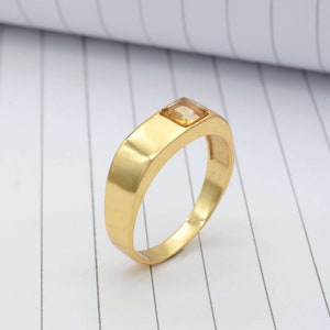 Peut inclure: Une bague en or avec une pierre précieuse carrée de couleur brun clair sertie au centre.